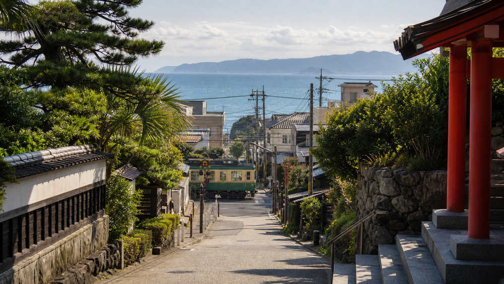 A coastal Japanese town street with a local train and ocean view